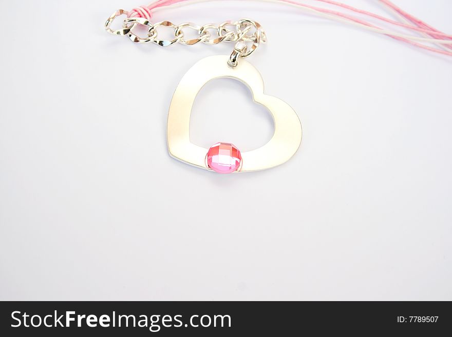 Necklace with heart medallion and pink stone on it.