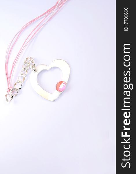 Necklace with heart medallion and pink stone on it.