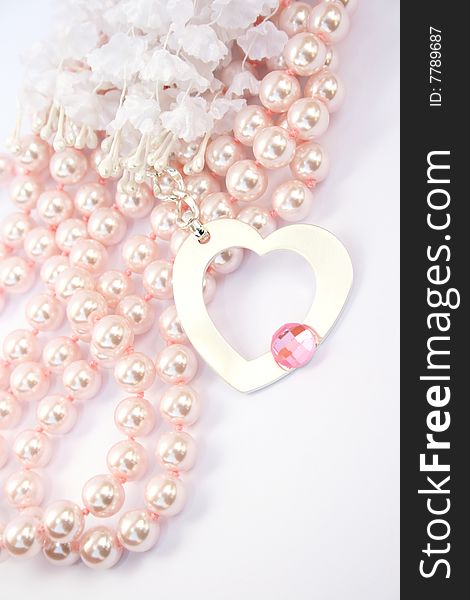 Necklace with heart medallion with pink stone on it, pink pearlsand white fabric flowers..