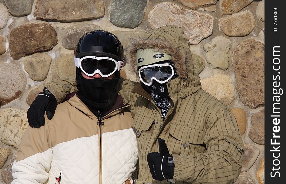 Skiers in Full Gear in Front of a Stone Wall