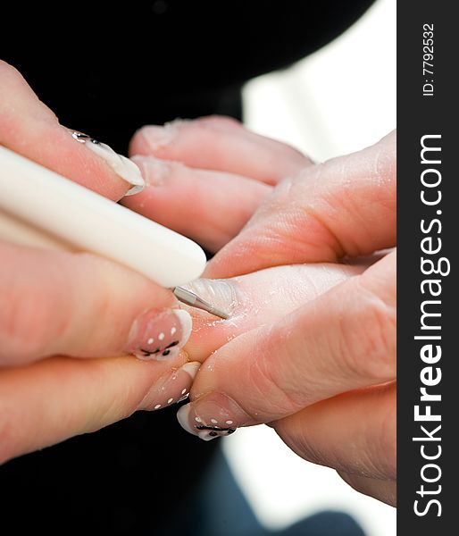 Foot therapist working on a pair of feet, removing dead tissue around the nail.