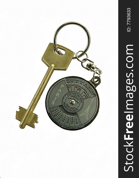 Key with a round, metallic trinket. On a trinket a calendar is represented. Key from a house.