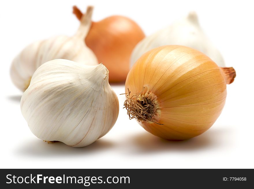 A few onions and garlic are isolated on a white background. Background blurred. A few onions and garlic are isolated on a white background. Background blurred.