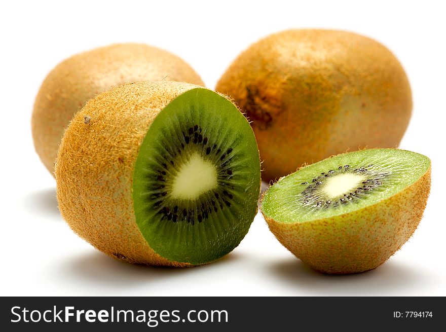Three kiwi isolated on a white background. At the forefront of a kiwi cut into two parts. Background blurred. Three kiwi isolated on a white background. At the forefront of a kiwi cut into two parts. Background blurred.