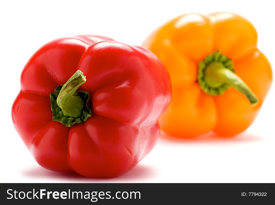 Red pepper isolated on a white background. In the background a yellow pepper. He blurred. Red pepper isolated on a white background. In the background a yellow pepper. He blurred.