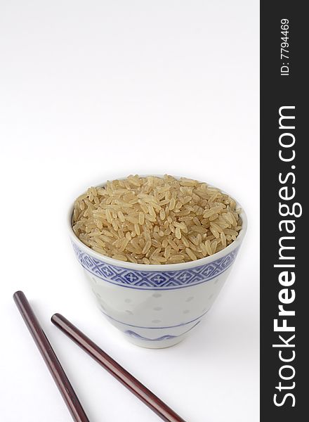 Long grain brown rice in a chinese cup, accessorized with chinese chopsticks