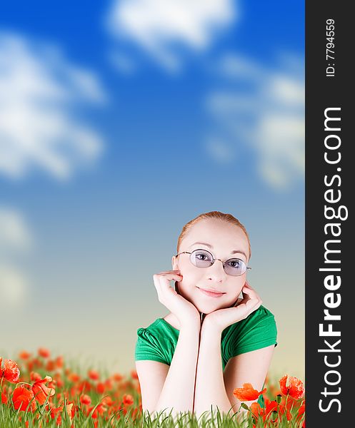 Smiling young woman lying in grass on a poppy flowers field. Smiling young woman lying in grass on a poppy flowers field