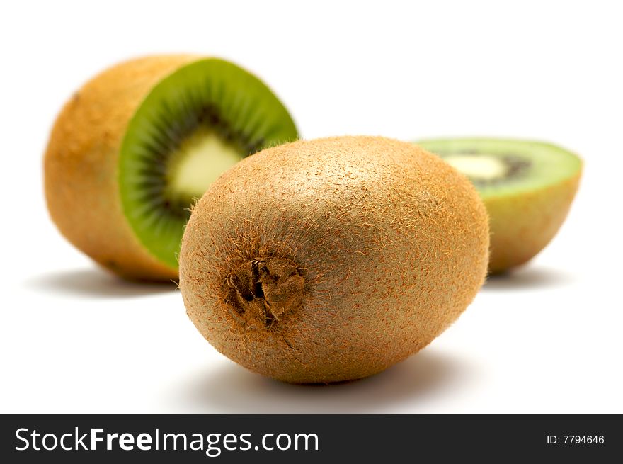 Two kiwi isolated on a white background. In the background kiwi cut into two parts. Background blurred. Two kiwi isolated on a white background. In the background kiwi cut into two parts. Background blurred.