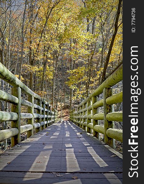 Wooden bridge crossing a creek in the middle of the forest during fall foliage. Wooden bridge crossing a creek in the middle of the forest during fall foliage.