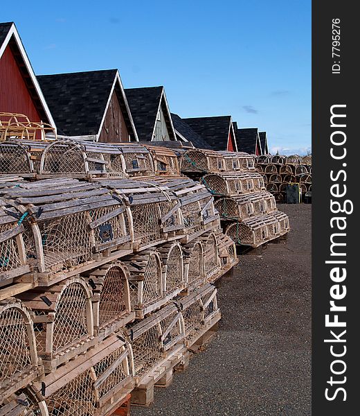 Lobster traps stacked on the wharf beside fishing shacks. Lobster traps stacked on the wharf beside fishing shacks.