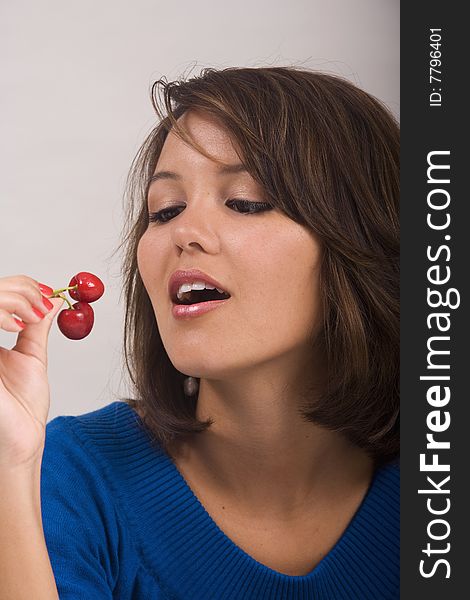 A beautiful young Asian-American girl eating red cherries