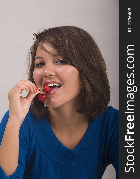 A beautiful young Asian-American girl eating red cherries