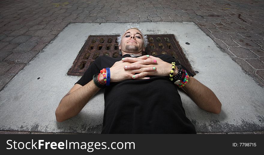 Man laying on a sewer cover. Man laying on a sewer cover