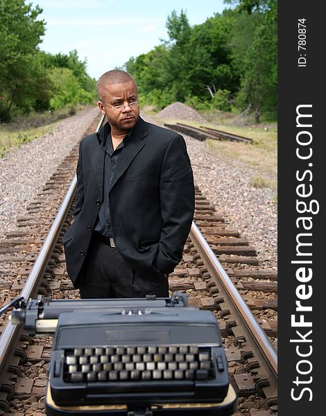 Young man with his typewriter on the train tracks. Young man with his typewriter on the train tracks.