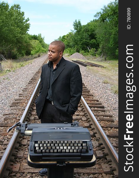 Young man with his typewriter on the train tracks. Young man with his typewriter on the train tracks.