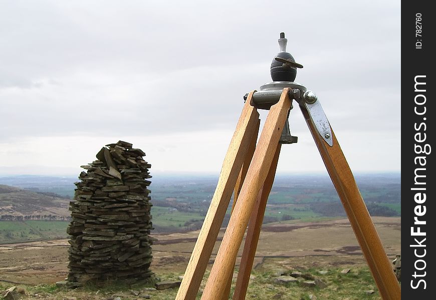 An old tripod next to a cairn on a hilltop. An old tripod next to a cairn on a hilltop