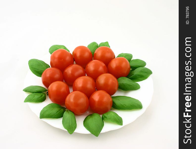 Some cherry tomatoes put together with fresh basil leaves. Some cherry tomatoes put together with fresh basil leaves
