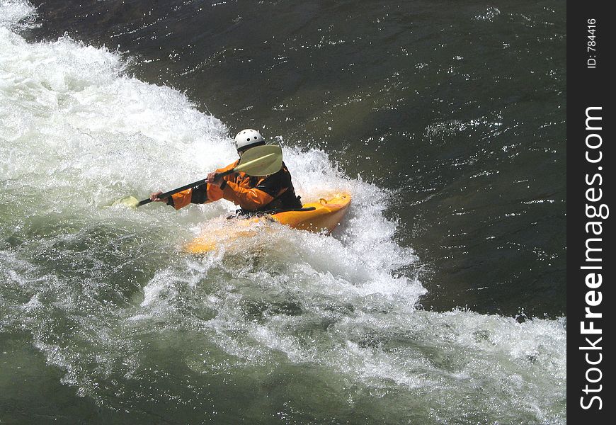 Determined kayaker charging the small rift in the river, forming a frothing, frenzied barrier. Determined kayaker charging the small rift in the river, forming a frothing, frenzied barrier.