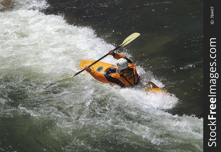 Determined kayaker charging the small rift in the river, forming a frothing, frenzied barrier. Determined kayaker charging the small rift in the river, forming a frothing, frenzied barrier.