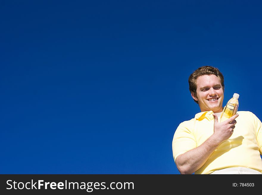 Happy Man looks at his bottle of water under a blue sky