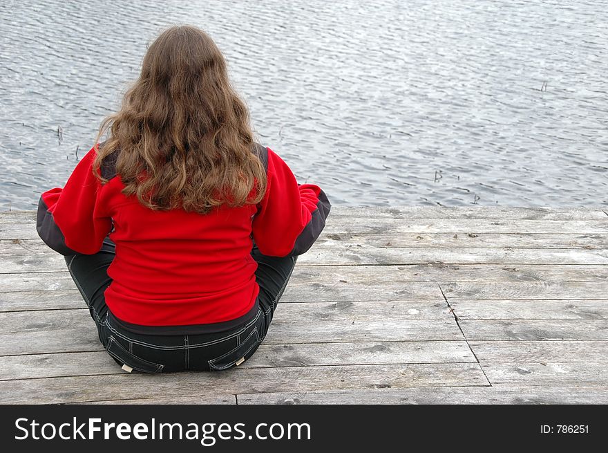 Blonde sitting cross-legged on the jetty. She is lost in meditation. Blonde sitting cross-legged on the jetty. She is lost in meditation.