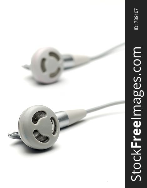 Silver earphones isolated on white, focus on near one