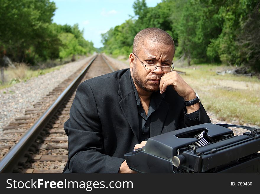 Young man with his typewriter on the train tracks. Young man with his typewriter on the train tracks.