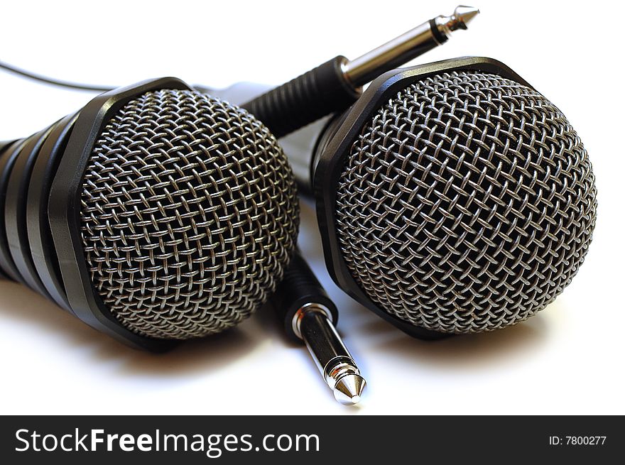 Two black wired karaoke microphones with gray metal grill on isolated background. Two black wired karaoke microphones with gray metal grill on isolated background.