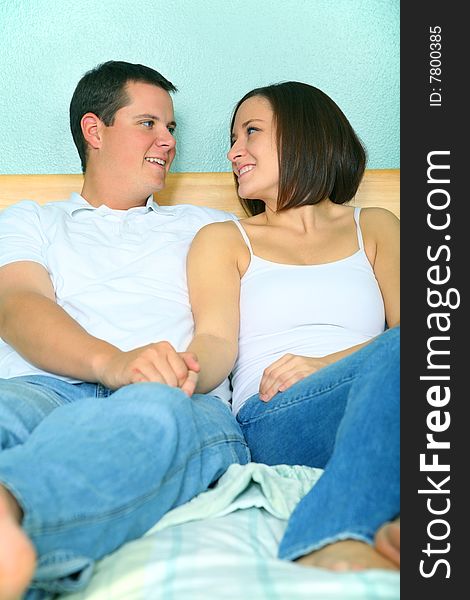 Romantic young caucasian couple holding hand and sit on their bed showing happy expression. Romantic young caucasian couple holding hand and sit on their bed showing happy expression