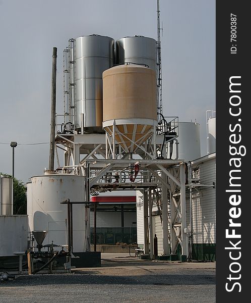 A pull-through setup for loading liquids onto trucks. various tanks, full station view with large tank and buildings. vertical view. A pull-through setup for loading liquids onto trucks. various tanks, full station view with large tank and buildings. vertical view