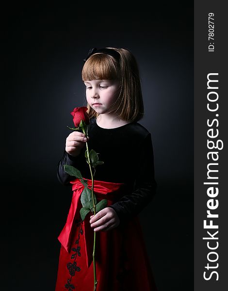 Pretty young girl smelling a long stemmed rose