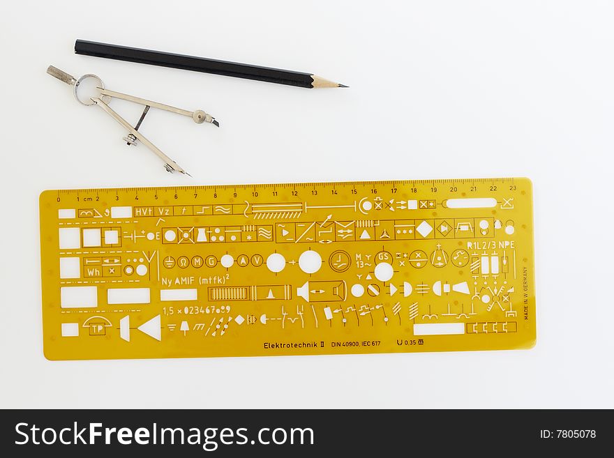 Drafting instruments and an electronic symbol stencil on a piece of paper. Two pairs of compasses a stencil and a pencil are laid out in a symmetrical pattern. Drafting instruments and an electronic symbol stencil on a piece of paper. Two pairs of compasses a stencil and a pencil are laid out in a symmetrical pattern.