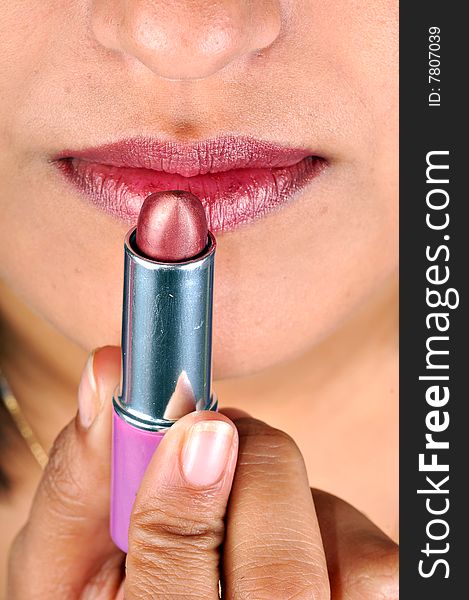 Model applying lipstick in studio.