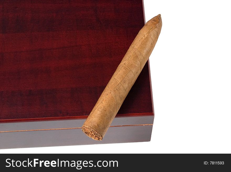 A torpedo shaped cigar resting on a dark colored cherrywoood humidor, photographed against black. A torpedo shaped cigar resting on a dark colored cherrywoood humidor, photographed against black.