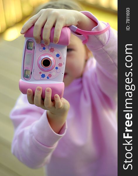 Little girl holding a pink camera taking pictures. Little girl holding a pink camera taking pictures