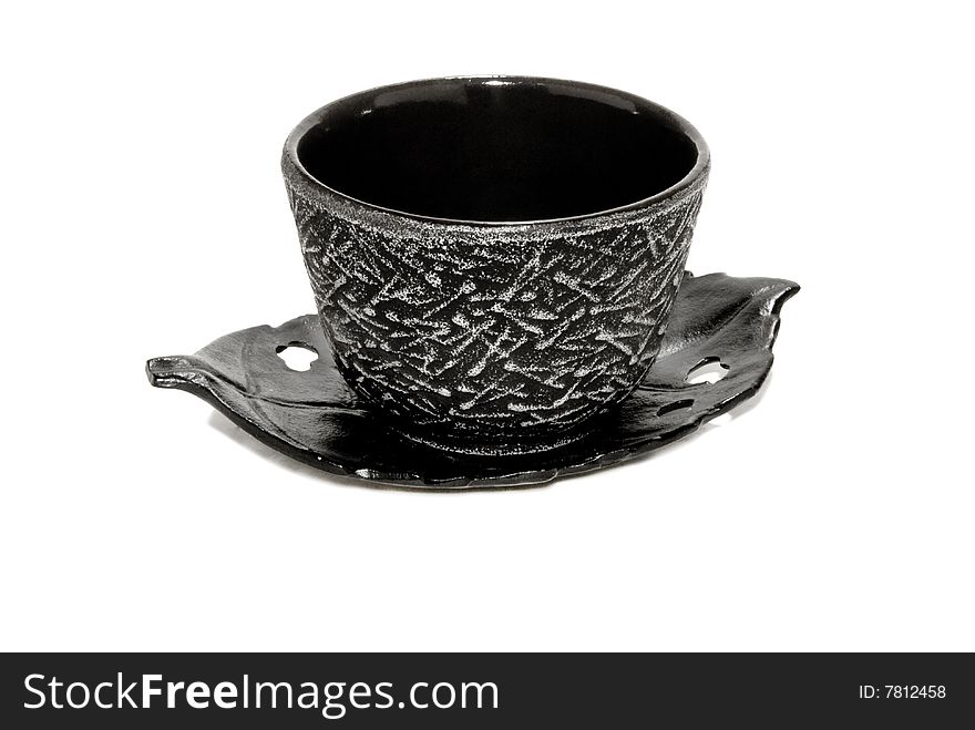 Black teacup with white lined designs on a black saucer that is shaped like a leaf. Isolated on a white background. Black teacup with white lined designs on a black saucer that is shaped like a leaf. Isolated on a white background.