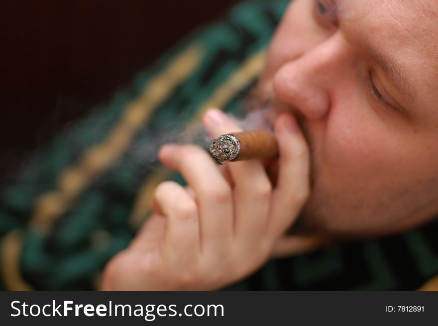 Man in dressing gown smokes cigar. Focus on cigar
