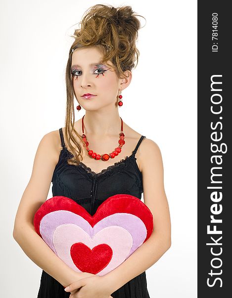 Fashion girl with red necklace and black top holding a valentine's day heart shaped pillow in her hand. Fashion girl with red necklace and black top holding a valentine's day heart shaped pillow in her hand