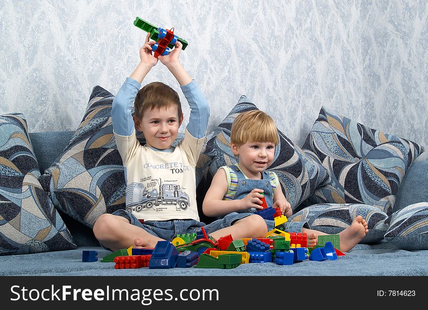 Two boys sitting on a sofa play toys. Two boys sitting on a sofa play toys