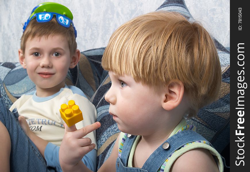 Two boys sitting on a sofa play toys. Two boys sitting on a sofa play toys