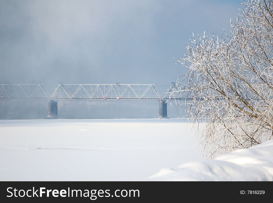 Winter view on the riverside with railway bridge