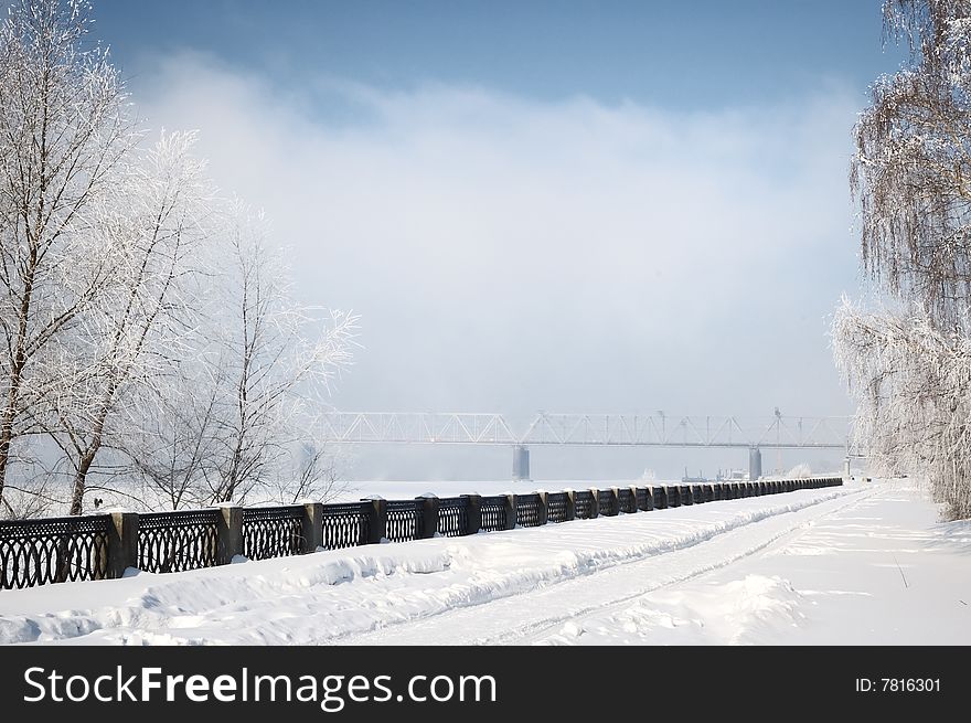 Winter view on the riverside with railway bridge