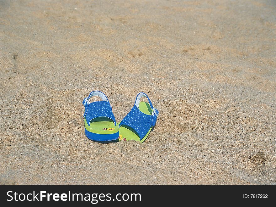 A pair of children sandals laying lost on the beach. A pair of children sandals laying lost on the beach