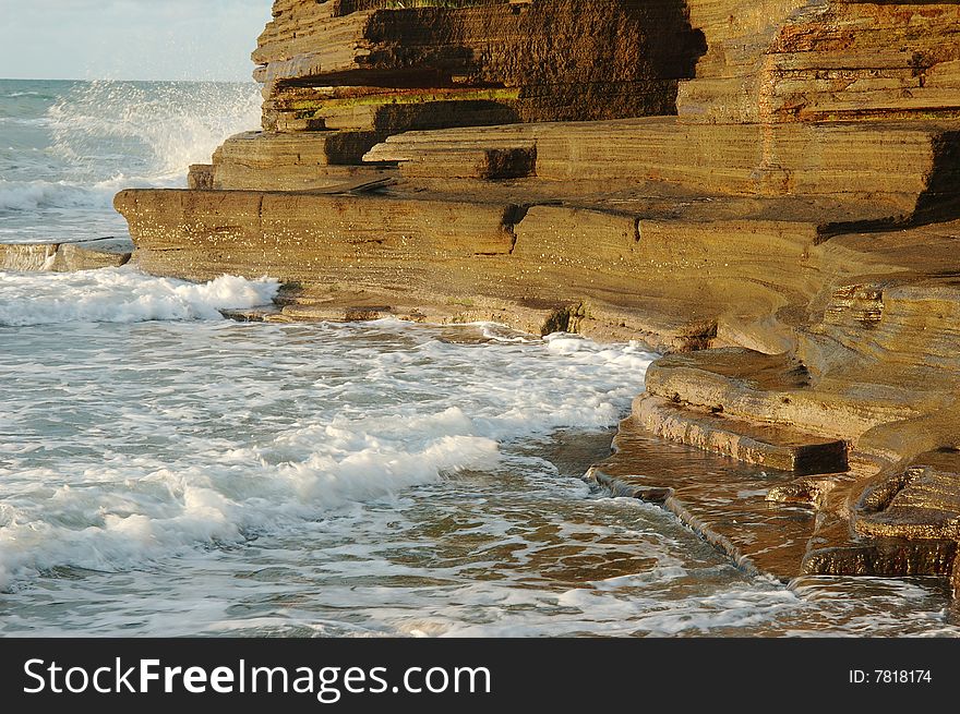 There are reefs by the seaside.The wave taps reef to arise a spray, the spray is under the irradiation of sunlight very beauty. There are reefs by the seaside.The wave taps reef to arise a spray, the spray is under the irradiation of sunlight very beauty.