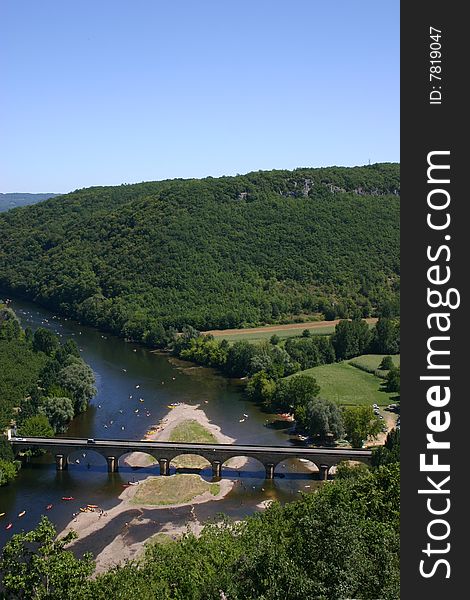 Image of canoes making their way down the river under a bridge. Image of canoes making their way down the river under a bridge