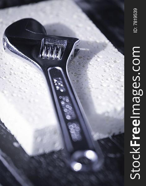 Conceptual black and white image of an adjustable wrench on a soft sponge. Conceptual black and white image of an adjustable wrench on a soft sponge