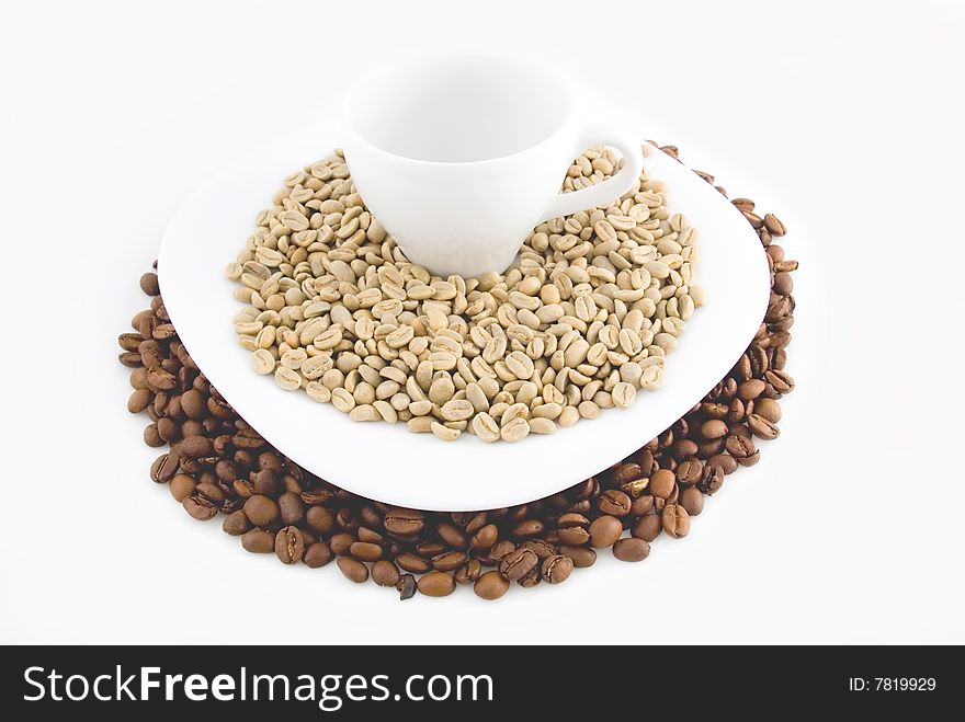 Combination of not fried and fried grains of coffee on a plate with a white coffee mug