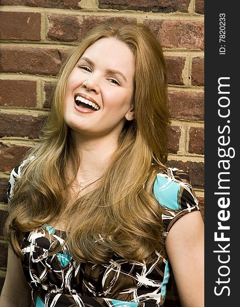Young Woman Laughing Against Brick Background