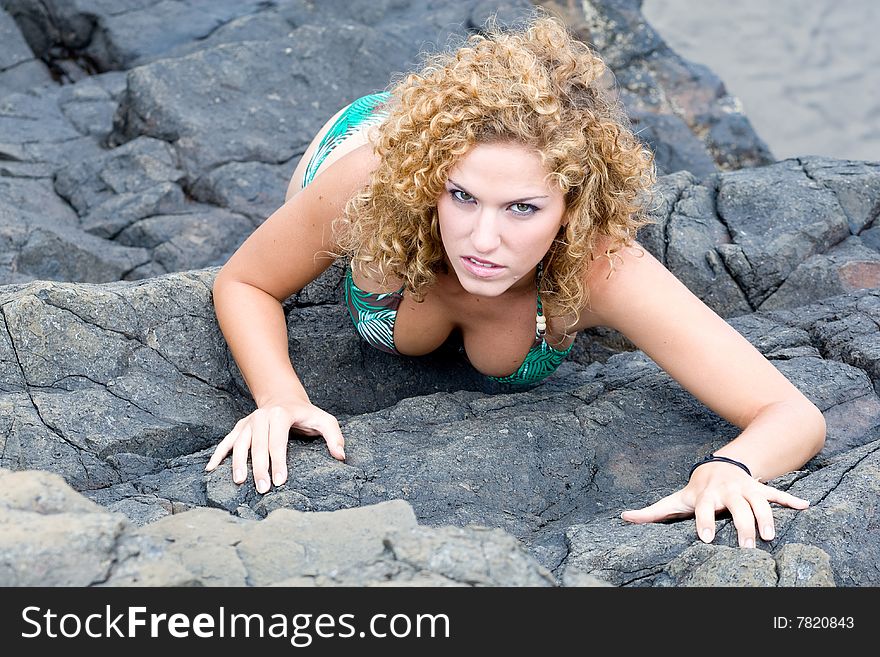 A girl stands by the rocks on the beach. A girl stands by the rocks on the beach