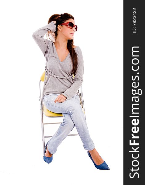 Front view of young model sitting on chair on an isolated background